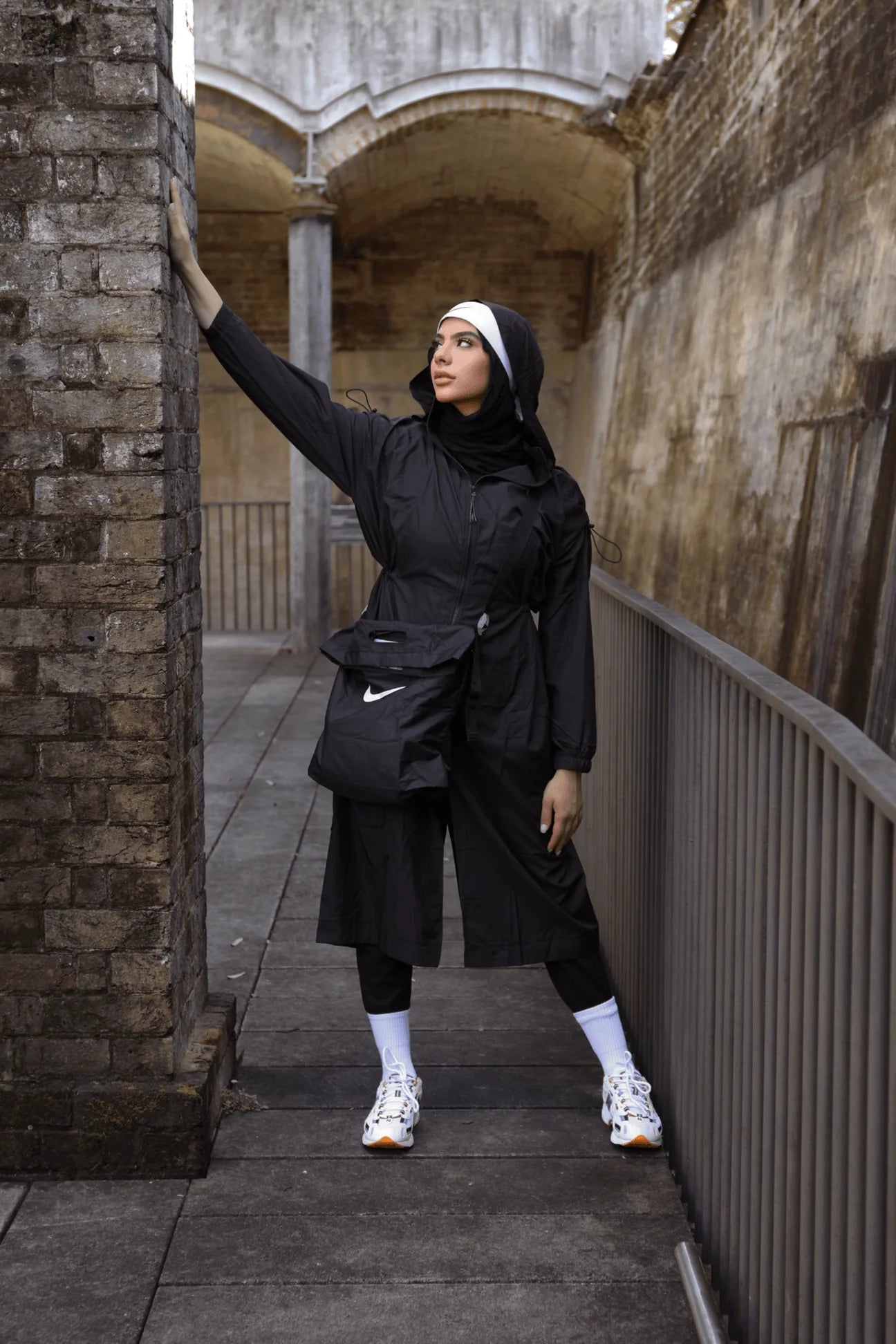 Woman in black outfit with Nike bag standing in an urban setting